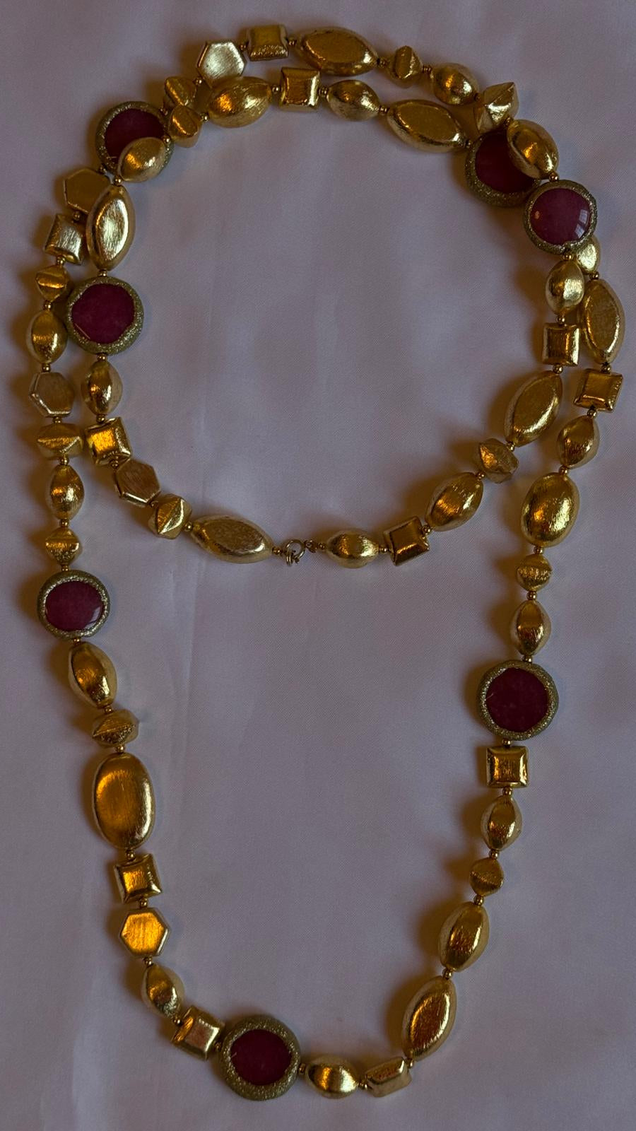 Gold necklace with red stones on a white background